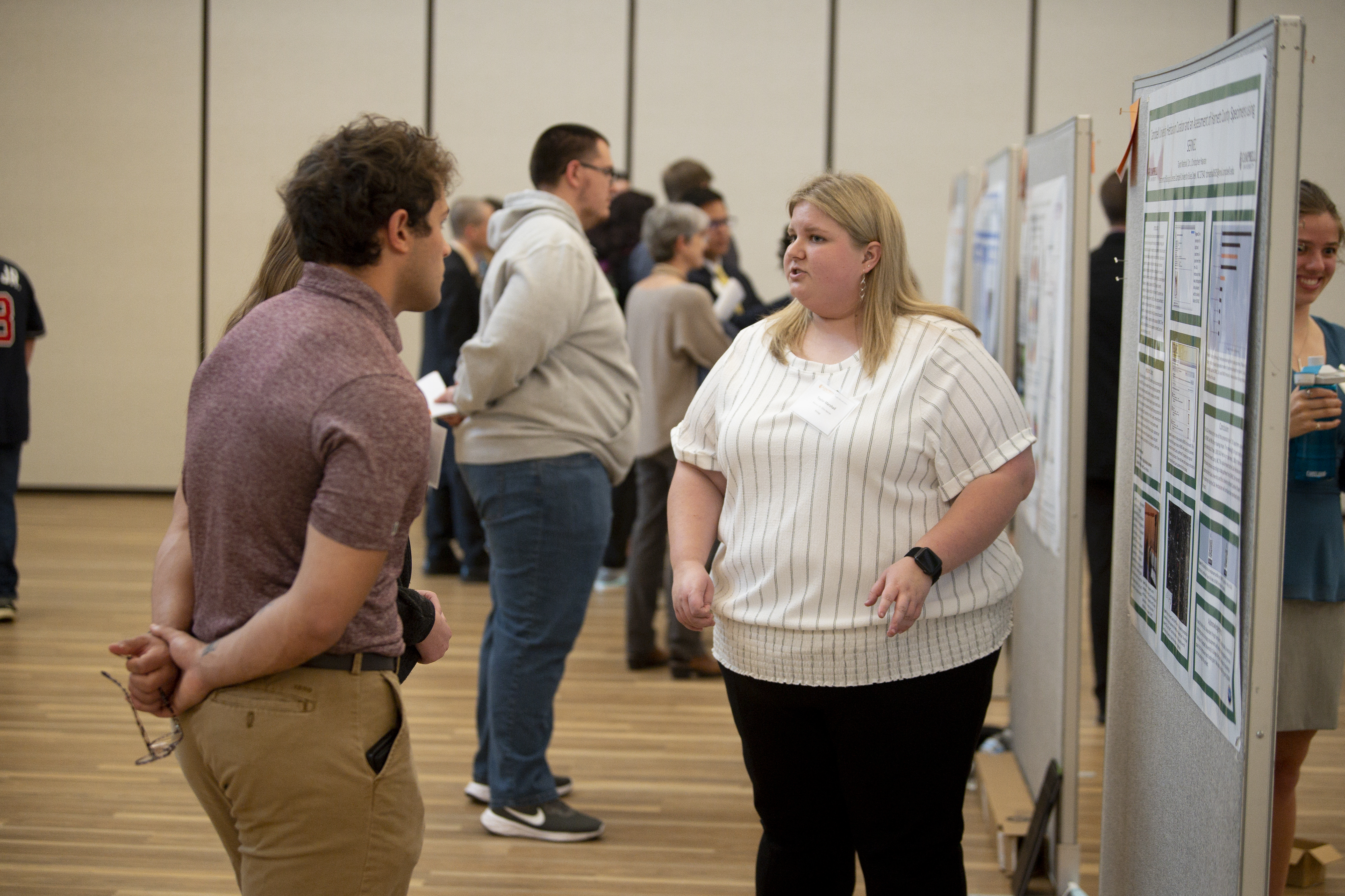 Symposium presenter discusses poster with a student